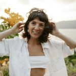 a woman in a white shirt is holding her hair