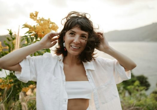 a woman in a white shirt is holding her hair